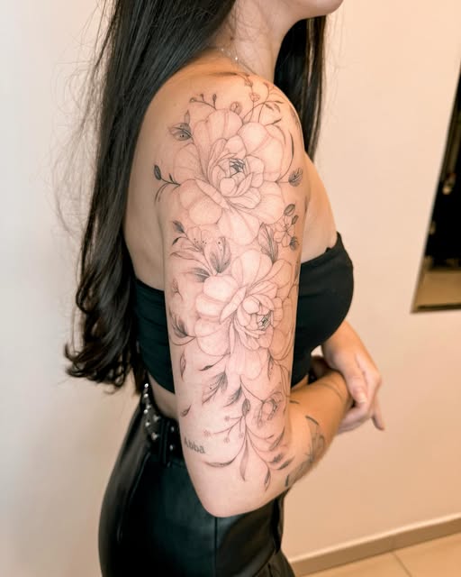 Composição floral de peônias e lírios em fine line cobrindo o braço